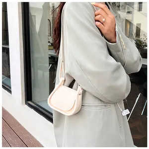 Dettaglio di una mini borsa in pelle PU color crema abbinata a un blazer verde salvia