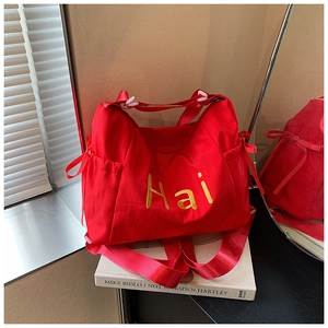 Detail of red fabric tote bag with yellow Hai embroidery and stylish drawstring bow