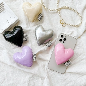 Puffy heart-shaped leather phone socket grips in five colors on a white fabric backdrop