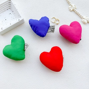 Detail of four plush heart phone grips in blue, green, red, and pink on a white tray