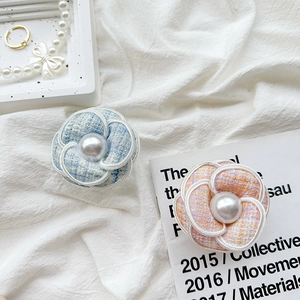 Detail of tweed camellia flower phone socket with pearl center and woven edges