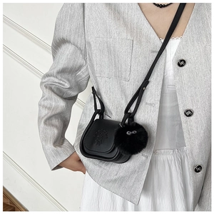 Détail du mini sac selle noir avec gaufrage chien et pendentif boule en peluche