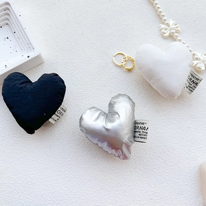 Close-up of heart-shaped fabric phone sockets in black, silver, and white with creative tags