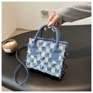 Nahaufnahme der blau-weiß karierten Canvas-Handtasche mit ausgefransten Kanten und Griffen