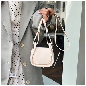 Dettaglio della mini borsa a sella bianco crema con bordi decorativi e tracolla