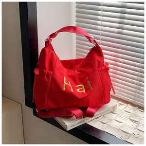 Detail of red nylon handbag featuring yellow Hai embroidery and side drawstring accents