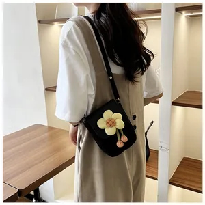 Détail du sac à bandoulière noir avec grande fleur jaune 3D et pompons roses