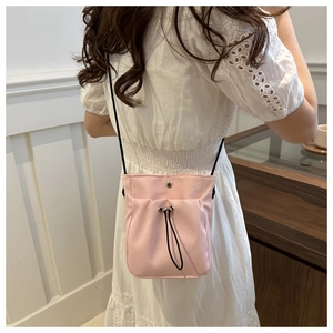 Detail van roze nylon mini crossbody tas met trekkoord ontwerp en zwart koord bandje