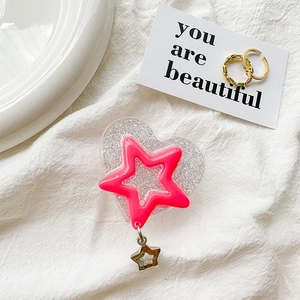 Detail of pink glitter heart phone grip with star pendant on white fabric