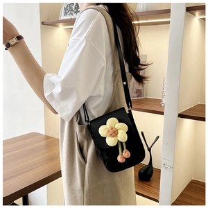 Détail du petit sac noir avec motif tournesol et breloques pompons roses