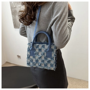 Detailansicht der karierten Denim-Schultertasche mit Fransenkanten und schmalen Riemen