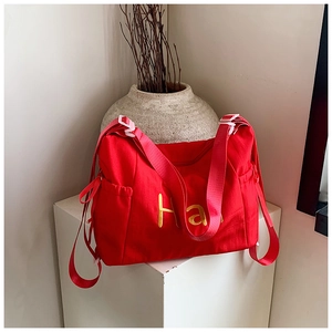 Detail of red canvas bag featuring yellow Han embroidery and red drawstring side pocket