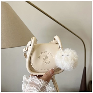 Détail du sac besace beige en cuir avec motif gaufré et pendentif pelucheux blanc