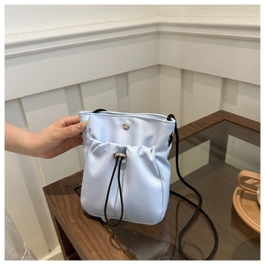 Detail of light blue mini canvas phone bag featuring a black drawstring front pocket