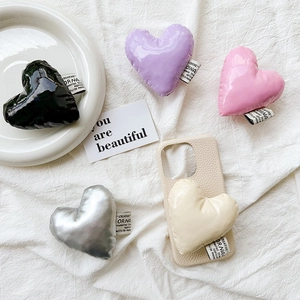 Detail of heart-shaped puffer leather phone sockets in black purple pink and cream