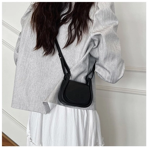 Dettaglio di una mini borsa a tracolla nera minimalista indossata da una modella