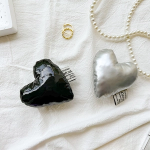 Detail of heart-shaped faux leather phone grips in glossy black and silver finishes