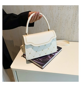 Detail of cream crossbody bag featuring heart-shaped quilting and gold metal accents