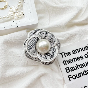 Detail of tweed camellia phone grip with pearl accent on a minimalist bauhaus background