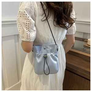 Detail van lichtblauwe mini crossbodytas met trekkoord, satijntextuur en zwarte riem