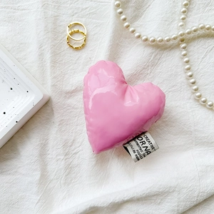 Detail of a pink heart-shaped padded phone grip with glossy finish on linen background