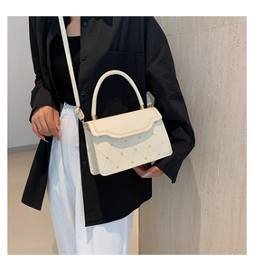 Detail of beige quilted square bag with gold heart studs and top handle