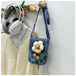 Détail du sac bandoulière bleu à fleurs avec fleur 3D jaune et pompons orange vifs