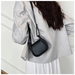 Borsa a tracolla nera minimalista abbinata a un blazer grigio per uno stile moderno