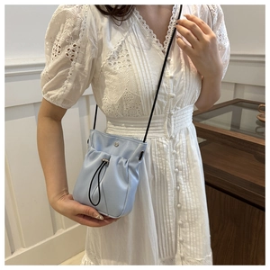 Detail van lichtblauwe crossbody emmerstas met trekkoord en smalle schouderband