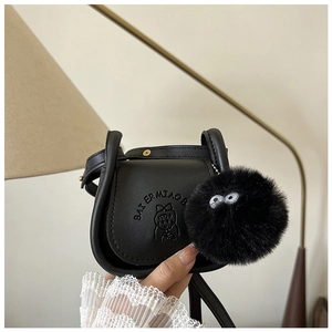 Détail d'un sac selle noir en cuir avec gaufrage dessin animé et accessoire en peluche