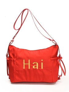 Large red nylon commuter bag with gold Hai embroidery and side drawstring detail