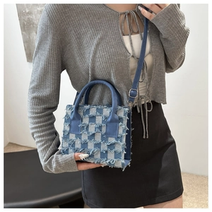 Nahaufnahme der blauen karierten Jeans-Handtasche mit ausgefransten Kanten und Metalldetails