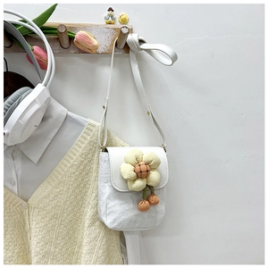 Détail d'un sac bandoulière blanc avec une grande fleur en 3D et des pompons orange