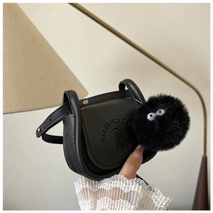 Détail d'un mini sac à bandoulière noir avec logo embossé et breloque en peluche mignonne
