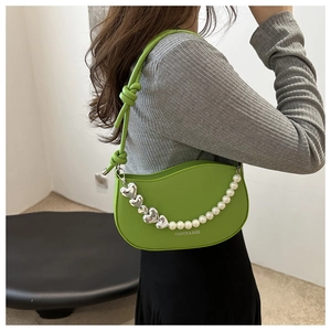 Détail d'un sac bandoulière croissant vert vif avec chaîne en perles et logo mode