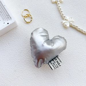 Close-up of metallic silver heart phone grip with textile texture and side woven label