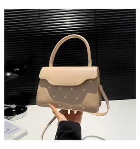 Detail of beige quilted PU leather crossbody bag with heart embroidery and golden hardware