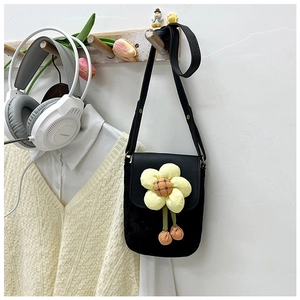 Détail d'un mini sac bandoulière noir avec une fleur décorative en peluche jaune