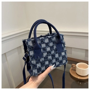 Detail einer karierten Jeans-Handtasche mit Fransenkanten und Stoffgriffen