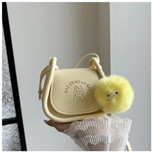 Détail du sac selle en cuir jaune clair avec gaufrage de fille de dessin animé et pompon