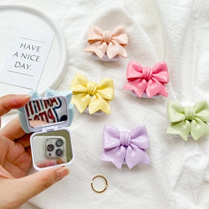 Close-up of Macaron bow phone grip with built-in folding cosmetic mirror on white fabric