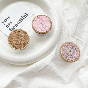 Detailed close-up of woven raffia cell phone socket grips in mixed colors