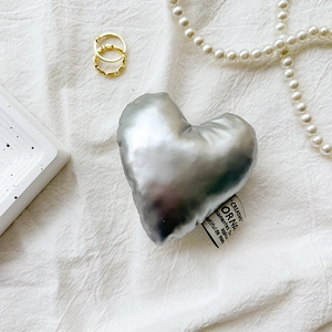 Close-up of heart-shaped silver metallic phone grip with elegant fabric brand label