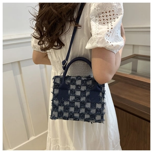 Details der Denim-Umhängetasche mit Karomuster, Fransenkanten und Schultergurt