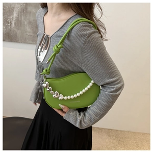 Detail of bright green crescent shoulder bag with pearl heart chain on female model