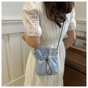 Detail van lichtblauwe crossbodytas met trekkoord, zacht nylon en zilveren gesp-sluiting