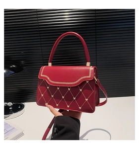 Detailed view of red glossy leather bag with golden heart quilted patterns and hardware