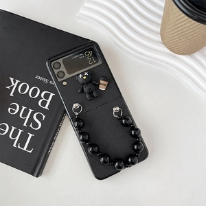 Detail of Samsung Z Flip case with 3D teddy bear charm and black beaded handle strap