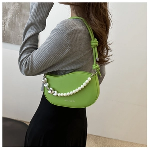 Detail of bright green crescent bag with heart metal and pearl decorative chain