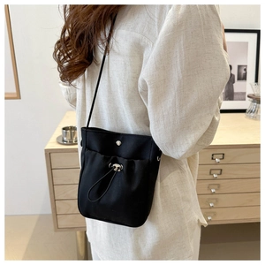 Minimalistische zwarte crossbody telefoontas met trekkoordzakje in een sfeervol interieur